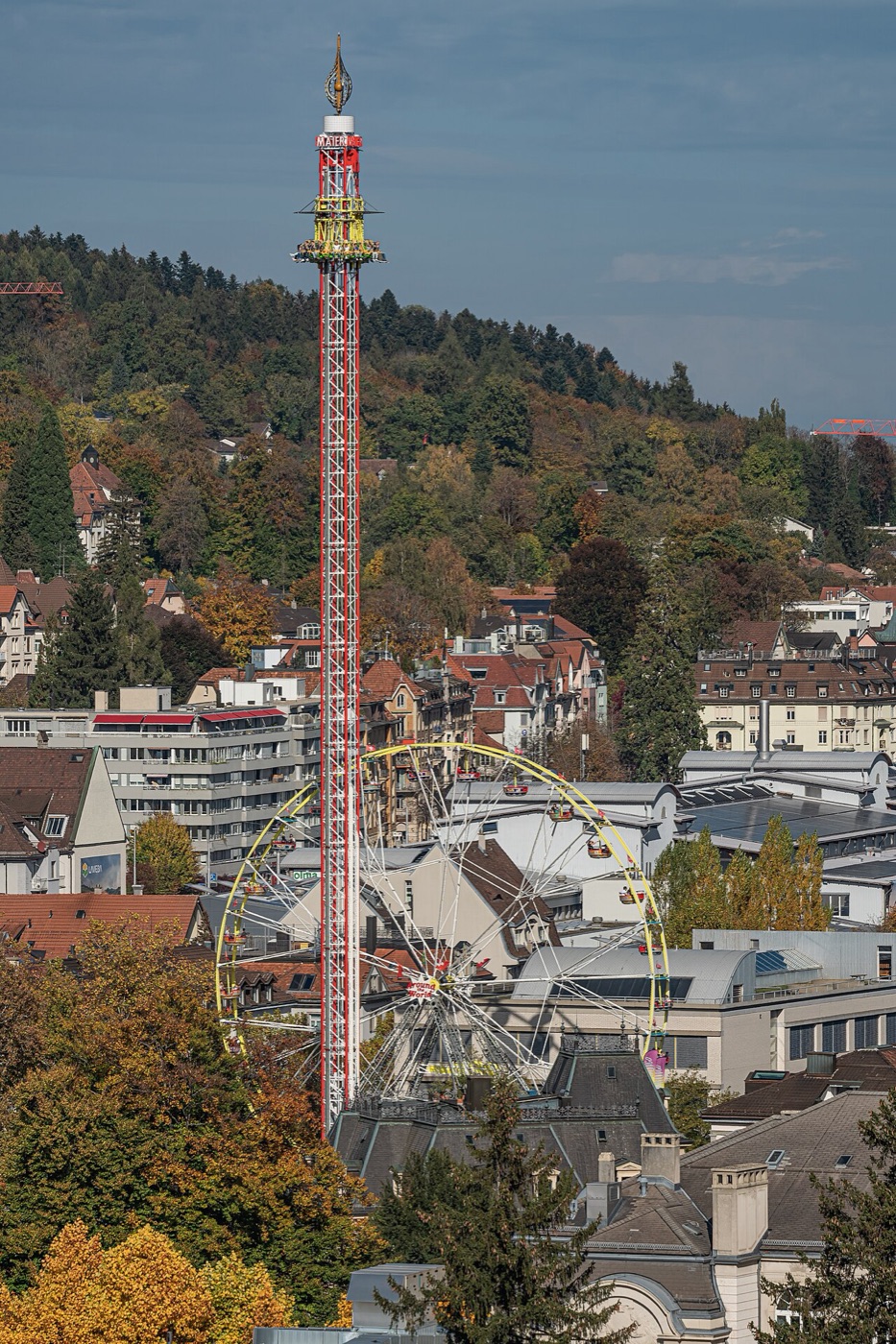 Riesenrad und rote Fallturm vo de Chilbi zmitzt i St. Gallen, im Herbst vo obe gseh.